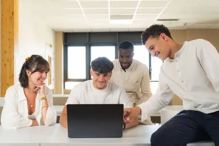Groupe de jeunes posant devant un ordinateur dans une salle de classe