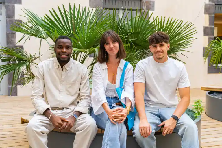 Photo de trois jeunes posant assis en extérieur.
